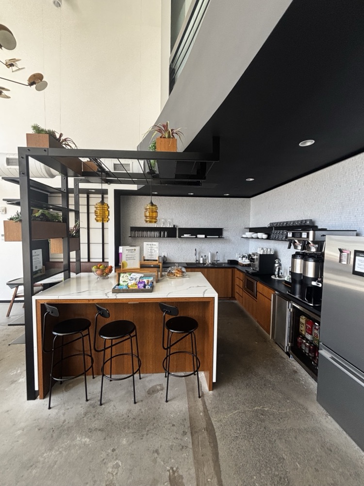 The kitchen, with a stone island, black stools, and coffee equipment along the counter.
