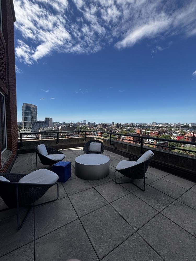 Woven chairs around a low round table on the terrace, with the Boston skyline behind.