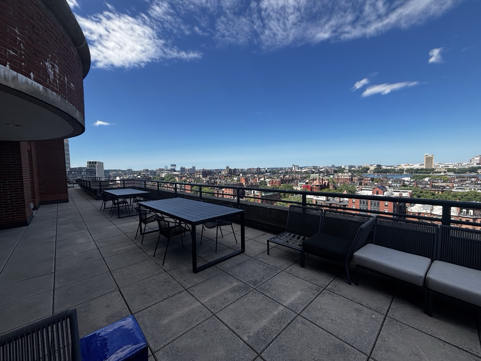 The rooftop terrace at 855 Boylston Street, with outdoor tables and lounge seating overlooking the Boston skyline.